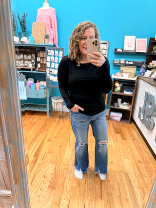 Person taking a mirror selfie in a store with shelves and decor in the background