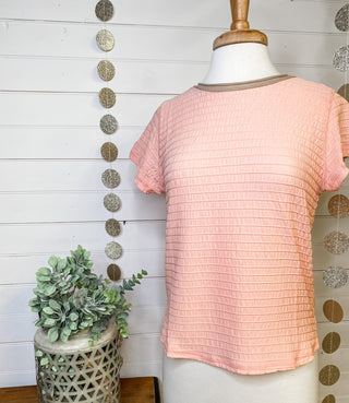 a peach short sleeve ruched style top with a taupe colored neckline